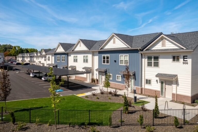 Row of modern townhomes with parking lot, landscaped lawn, and building number 906 on the right end unit