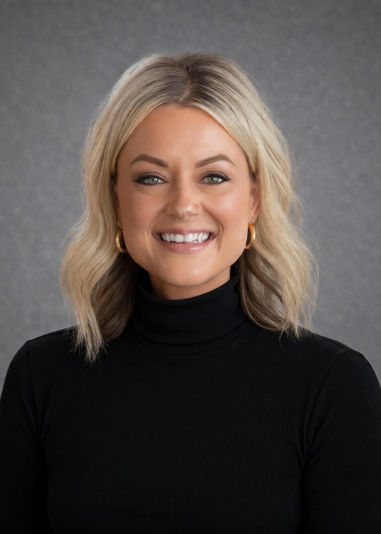 Headshot of Kayla Brown smiling in a black turtleneck against a gray studio background