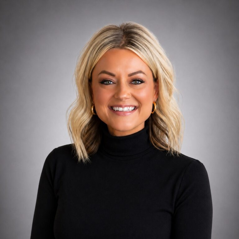 Smiling woman with shoulder-length blonde hair, gold hoop earrings, and a black turtleneck against a gray studio background